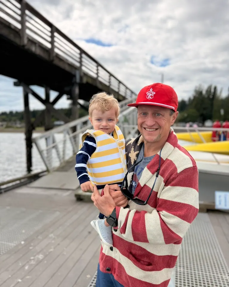 Jeff Reynolds holding his son on a dock by the water